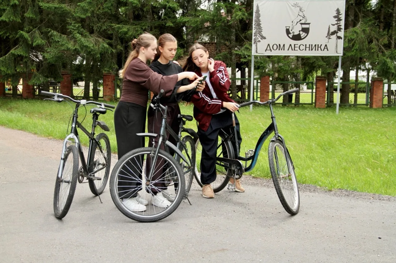Гости с велосипедами у вывески «Дом Лесника»